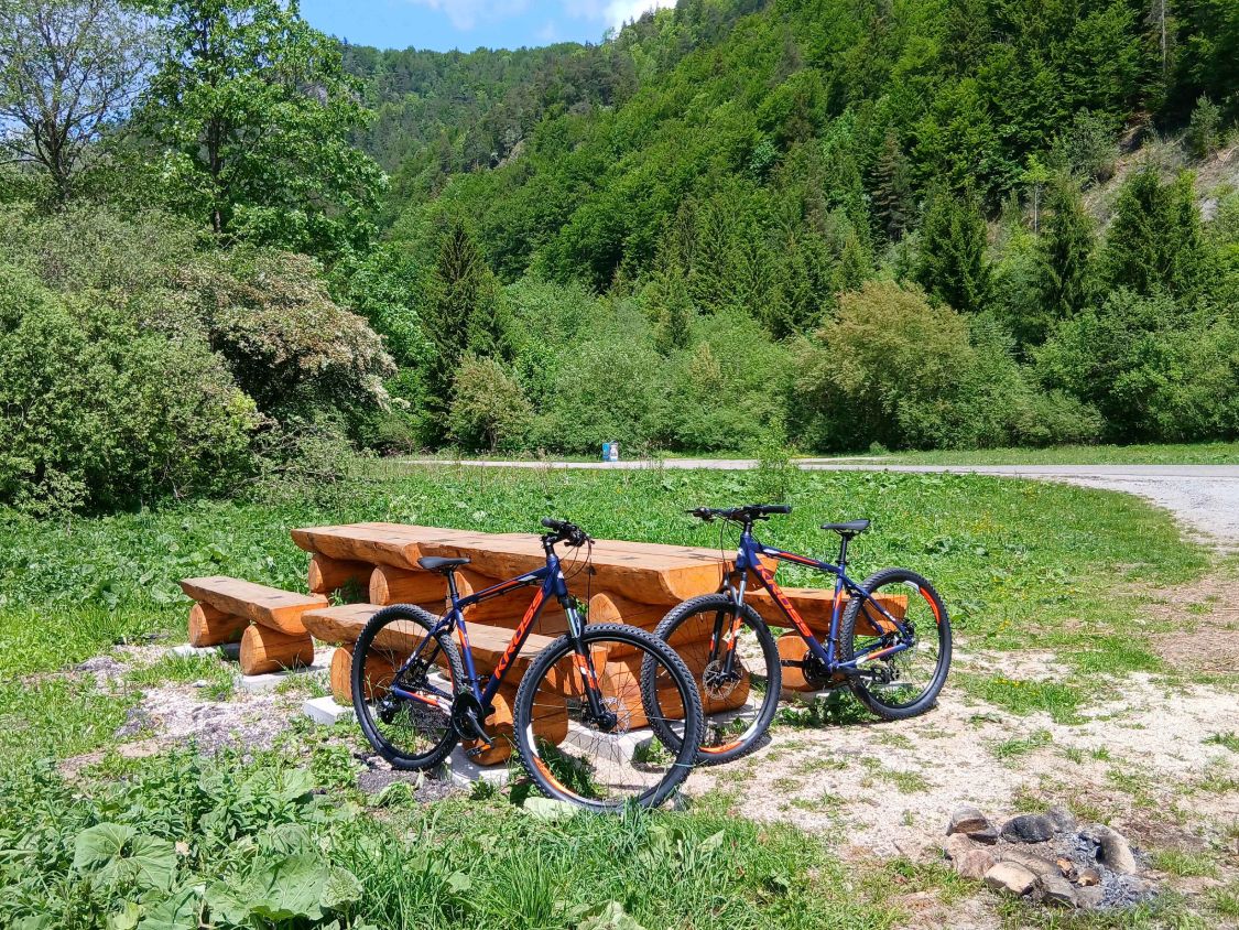 Dva bicykle Kross opreté o drevený stôl na oddychovom mieste v doline